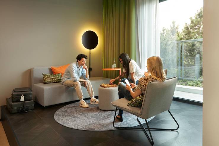 Drei Personen entspannen in der modernen Sitzecke der Replay Suite King im REVERB Hotel im Bunker.
