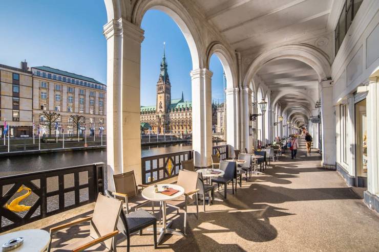Ausblick von der Außengastronomie der Alsterarkaden in Richtung Rathaus bei blauem Himmel.