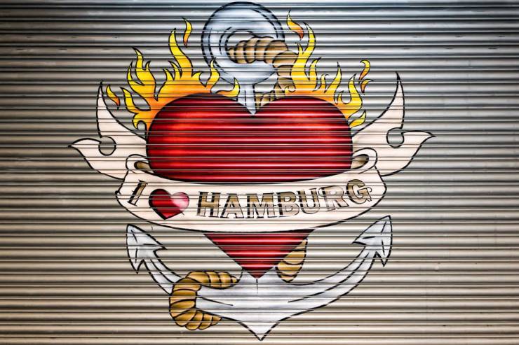 Flammendes Streetart-Herz mit Anker und "I love Hamburg"-Aufschrift auf einem geschlossenen Rolladen.