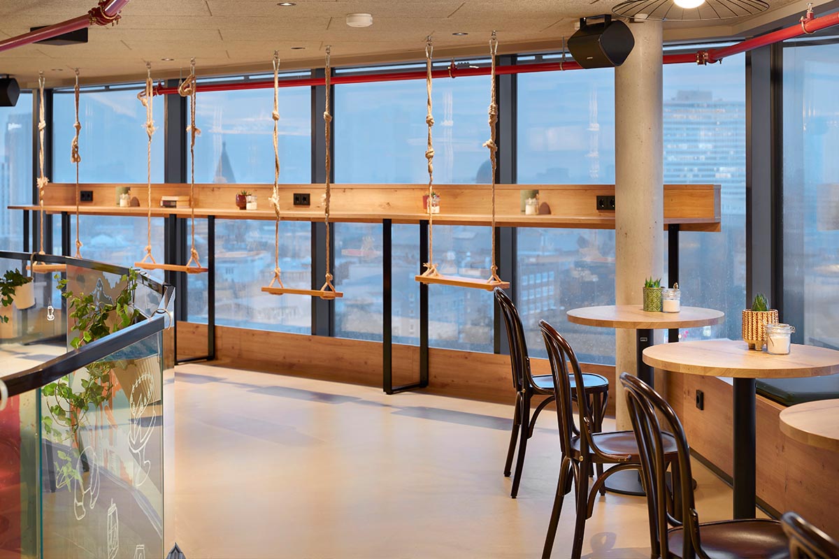 Kreative Sitzmöglichkeiten: Bartische mit Schaukeln statt Stühlen und Blick auf Hamburgs Dächer.